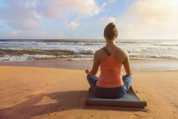 Mujer haciendo yoga al aire libre en la playa - Padmasana pose de loto
 - Foto, imagen