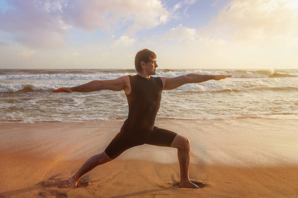 Mann macht Yoga Asana Virabhadrasana 1 Krieger Pose am Strand - Foto, Bild