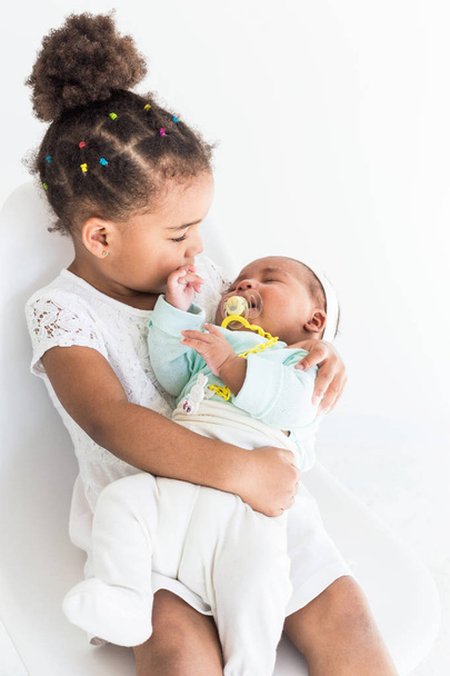 Little girl holding her sister in her arms on white background - Foto, Imagem