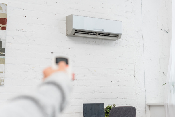 cropped shot of woman pointing at air conditioner with remote control - Photo, Image
