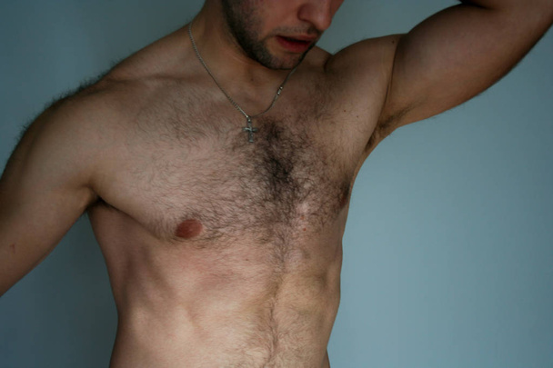 Мускулистый человек демонстрирует свои мускулы. Атлетик показывает грудь и живот.
. - Фото, изображение