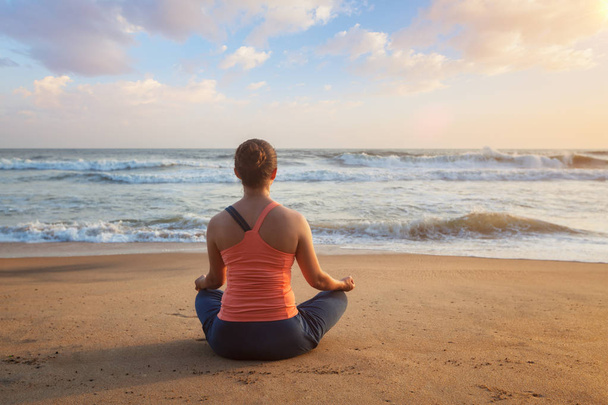 Frau beim Yoga-Lotus posiert draußen am Strand - Foto, Bild