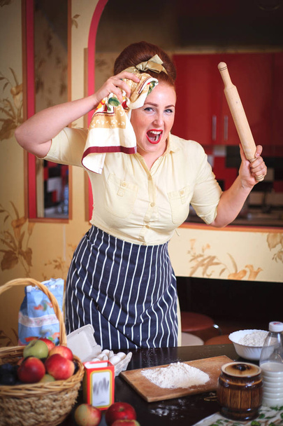 Femme expressive émotionnelle femme mignonne dans la cuisine. Dans les mains tenant des outils pour la cuisson des aliments
. - Photo, image
