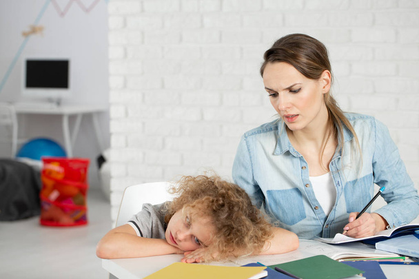 Nervous mother doing homework with bored kid with Asperger syndrome - Photo, Image