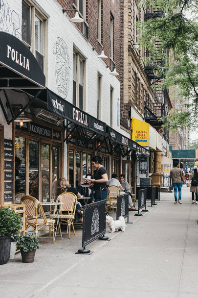 New York, Amerika Birleşik Devletleri - 29 Mayıs 2018: Garson Manhattan, New York şehrinin en yoğun nüfuslu borough restoranda açık masalarda oturan insanlar için yiyecek getiriyor. - Fotoğraf, Görsel