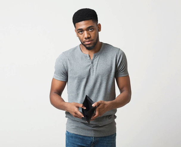 Homme afro-américain malheureux montrant portefeuille vide au studio
 - Photo, image