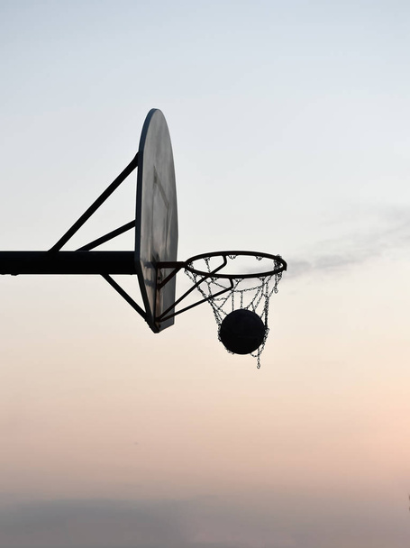Silhouette of a basketball hoop and backboard at sunset - Fotoğraf, Görsel