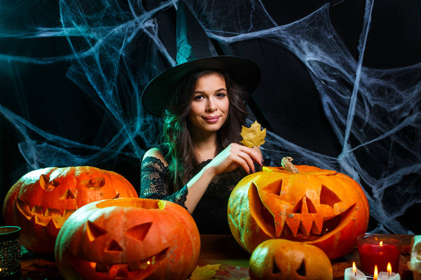 Halloween Witch concept - young woman with halloween sweet and candy with cheerful smiling over spider web and with curved pumpkins background. - Foto, afbeelding