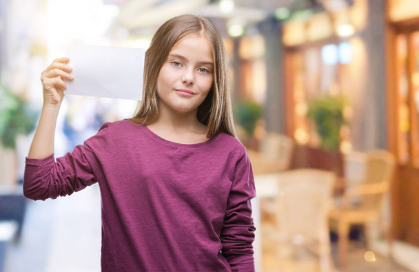Молодая красивая девушка держит чистую бумажную карточку на изолированном фоне с уверенным выражением на умном лице, думая серьезно
 - Фото, изображение