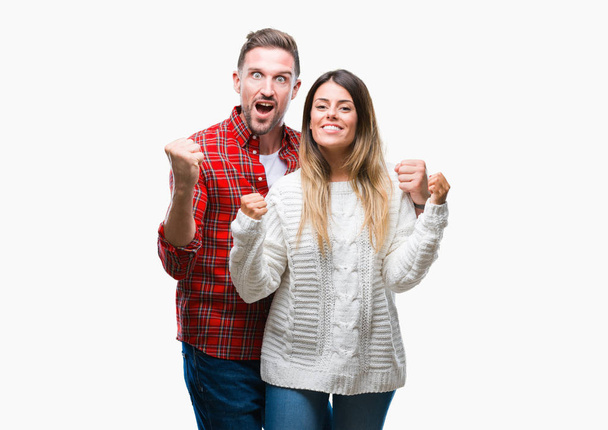 Молода пара закохана в зимовий светр над ізольованим тлом, що святкує здивований і вражений успіхом з піднятими руками і відкритими очима. концепція переможця
. - Фото, зображення