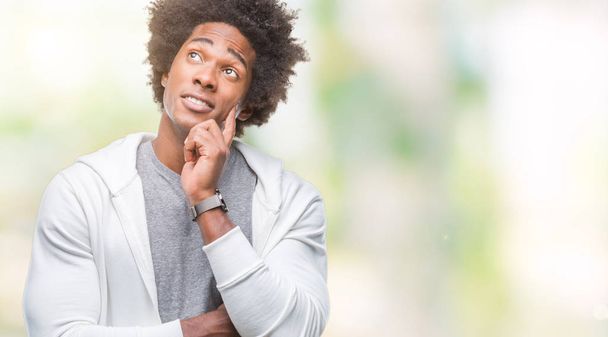 Афро американський людина носять толстовки над ізольований фону з рук на підборіддя, думаючи про питання, замислений вираз. Усміхаючись з вдумливі обличчя. Сумніву концепції. - Фото, зображення