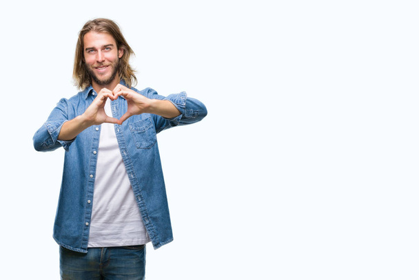 Young handsome man with long hair over isolated background smiling in love showing heart symbol and shape with hands. Romantic concept. - Photo, Image