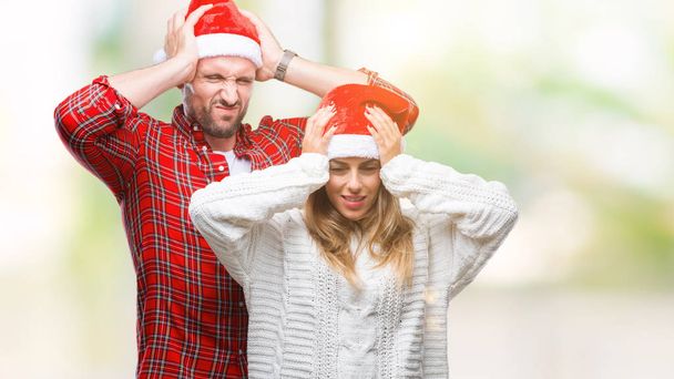 Noel giyen aşık genç çift şapka çünkü umutsuz ve stresli baş ağrısı acı izole arka plan üzerinde ağrı ve migren. Ellerini kafasına. - Fotoğraf, Görsel
