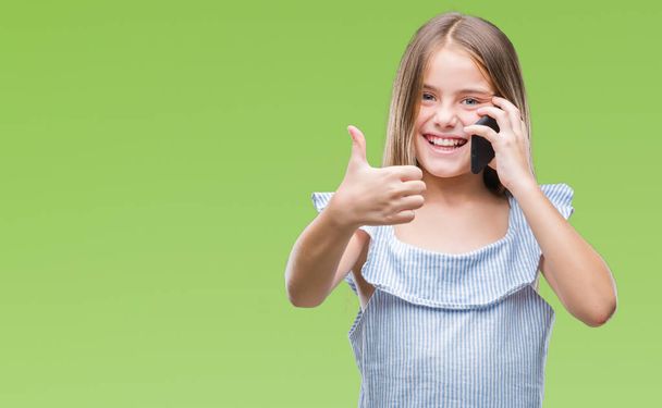 Young beautiful girl talking on the phone over isolated background happy with big smile doing ok sign, thumb up with fingers, excellent sign - Fotografie, Obrázek