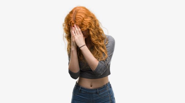 Young redhead woman with sad expression covering face with hands while crying. Depression concept. - Photo, Image