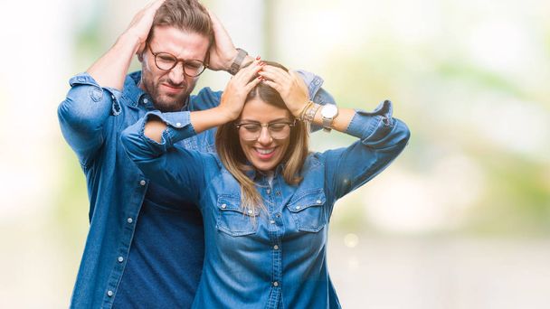 Young couple in love wearing glasses over isolated background suffering from headache desperate and stressed because pain and migraine. Hands on head. - Photo, Image
