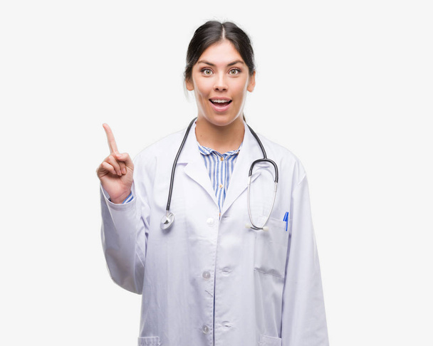 Giovane donna ispanica medico sorpreso con un'idea o una domanda che punta il dito con la faccia felice, numero uno
 - Foto, immagini