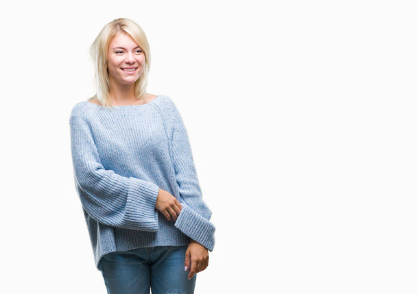 Young beautiful blonde woman wearing winter sweater over isolated background looking away to side with smile on face, natural expression. Laughing confident. - Photo, Image