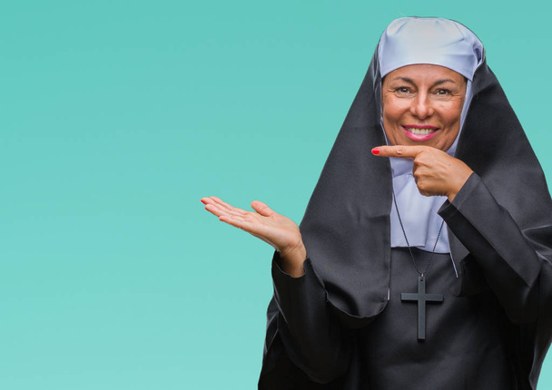 Monja católica cristiana mayor de mediana edad sobre un fondo aislado sorprendida y sonriendo a la cámara mientras se presenta con la mano y señalando con el dedo
. - Foto, Imagen