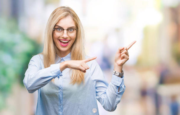 Mladá krásná blondýna obchodních žena nosí brýle izolované pozadí s úsměvem a při pohledu na fotoaparát s oběma rukama a prsty přejdete na stranu. - Fotografie, Obrázek