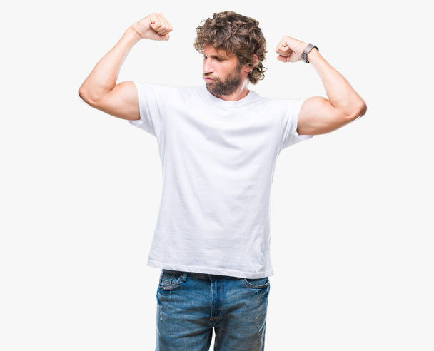 Knappe Spaanse model man over geïsoleerde achtergrond armen spieren glimlachend trots tonen. Fitness concept. - Foto, afbeelding