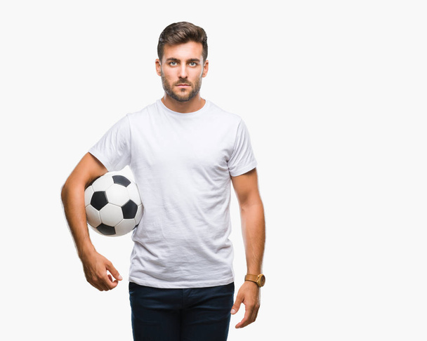 サッカー サッカー ボール考えて深刻なスマートの顔に自信を持って式に孤立した背景の上に保持している若いハンサムな男 - 写真・画像