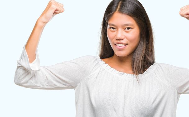 Young asian woman over isolated background showing arms muscles  - Foto, Imagen