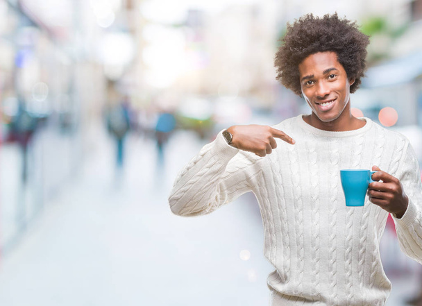 Afro-Américain homme buvant tasse de café sur fond isolé avec visage surprise pointant du doigt vers lui-même
 - Photo, image