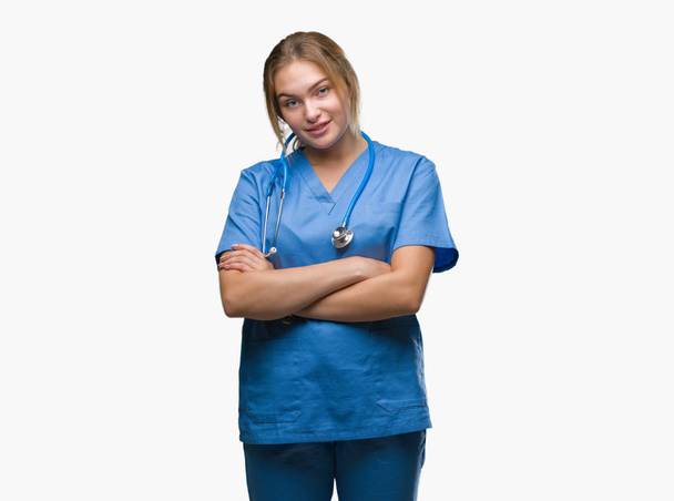 Young caucasian doctor woman wearing surgeon uniform over isolated background happy face smiling with crossed arms looking at the camera. Positive person. - Фото, изображение