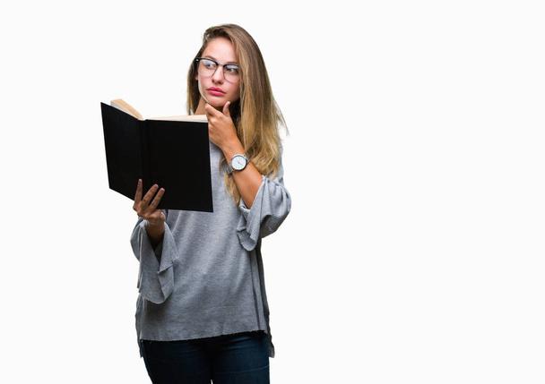 Молодая красивая блондинка читает книгу на изолированном фоне серьезное лицо, думая о вопросе, очень запутанная идея
 - Фото, изображение