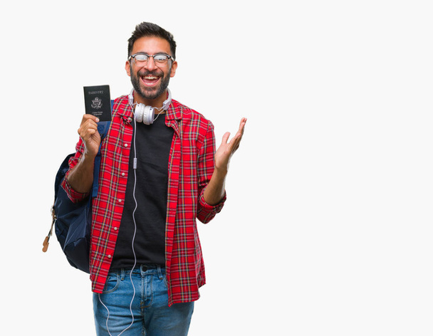 Adult hispanic student man holding passport of america over isolated background very happy and excited, winner expression celebrating victory screaming with big smile and raised hands - Foto, Imagen