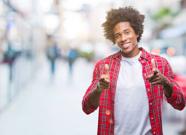 Afro american mężczyzna na białym tle wskazując palcami do aparatu z twarzy szczęśliwy i zabawny. Dobra energia i wibrafon. - Zdjęcie, obraz