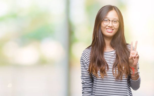 Młoda kobieta azjatyckich w okularach na białym tle Wyświetlono z palców numer dwa  - Zdjęcie, obraz