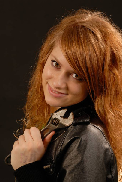 Portrait on a young red-haired woman, 25 years old, holding an adjustable wrench in Ystad, Scania, Sweden - Photo, Image