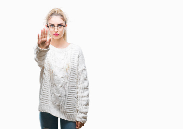 junge schöne blonde Frau trägt eine Brille über isoliertem Hintergrund und hört auf, mit der Handfläche zu singen. Warnausdruck mit negativer und ernster Geste im Gesicht. - Foto, Bild