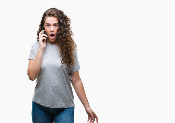 Young brunette girl talking on smartphone over isolated background scared in shock with a surprise face, afraid and excited with fear expression - Fotoğraf, Görsel