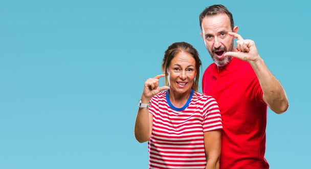 Middle age hispanic couple in love over isolated background smiling and confident gesturing with hand doing size sign with fingers while looking and the camera. Measure concept. - Foto, Imagem