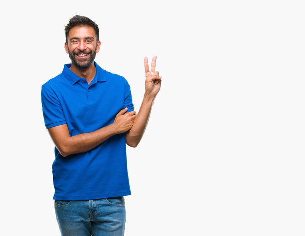 Volwassen Spaanse man over geïsoleerde achtergrond glimlachend met blij gezicht winking op de camera doen overwinning teken. Nummer twee. - Foto, afbeelding