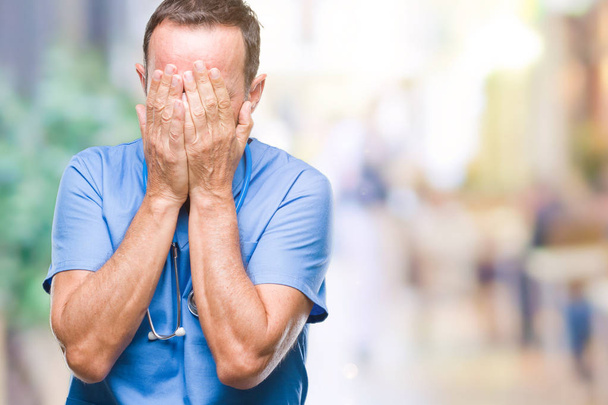 Otřepané vedoucí lékař muž středního věku uniformě zdravotní izolované pozadí se smutným výrazem pokrývající obličej rukama a plakat. Koncept deprese. - Fotografie, Obrázek