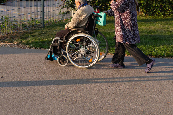 夜の南ドイツ春歴史的都市における日当たりの良い屋外の公園で車椅子の老夫婦 - 写真・画像