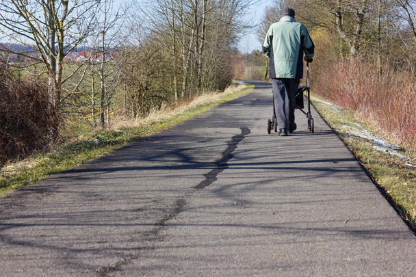 vanhempi mies rollator pyörätiellä ja aurinkoinen talvipäivä sininen taivas Etelä-Saksassa
 - Valokuva, kuva