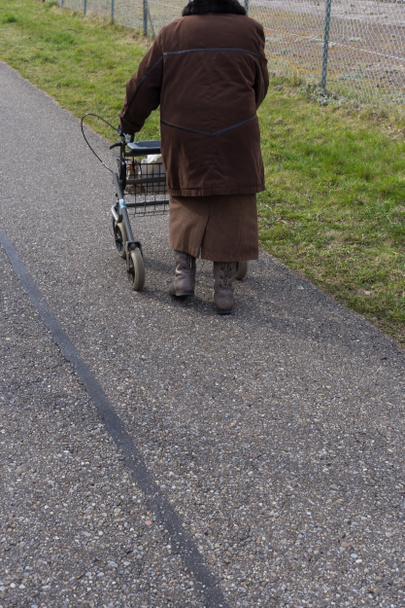 vanhempi nainen, jolla on rollator pyörällä pääsiäisenä keväällä Etelä-Saksassa
 - Valokuva, kuva