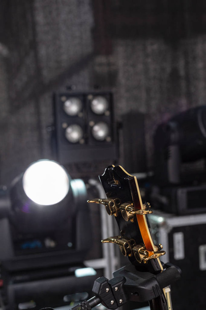 Details des Gitarristen auf der Bühne mit schwarzem Hintergrund und braunorangen Farben - Foto, Bild