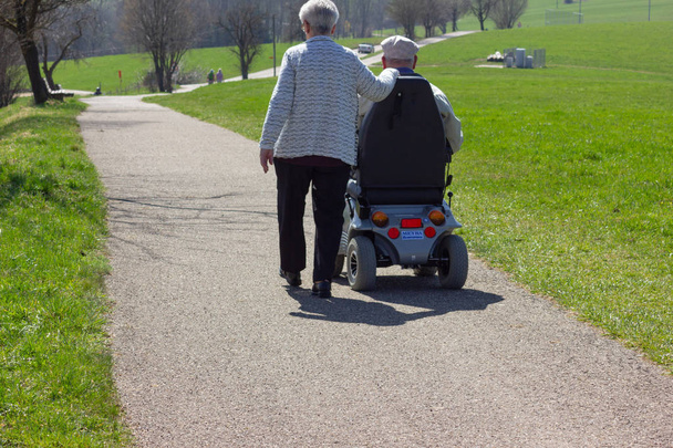 пожилая пара с моторизированной инвалидной коляской на голубом небе солнечный праздник в восточную весну в Южной Германии
 - Фото, изображение