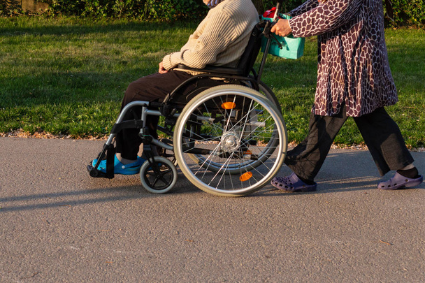 couple sénior avec fauteuil roulant dans le parc extérieur en Allemagne du sud printemps ville historique soirée ensoleillée
 - Photo, image