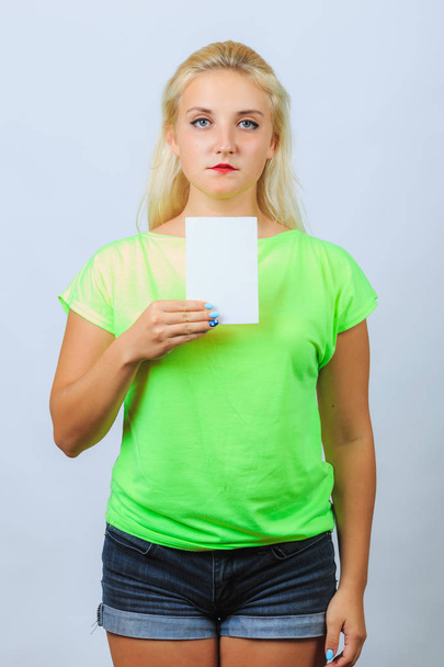 junges blondes Mädchen hält Flugblatt mit Kopierplatz in der Hand - Foto, Bild
