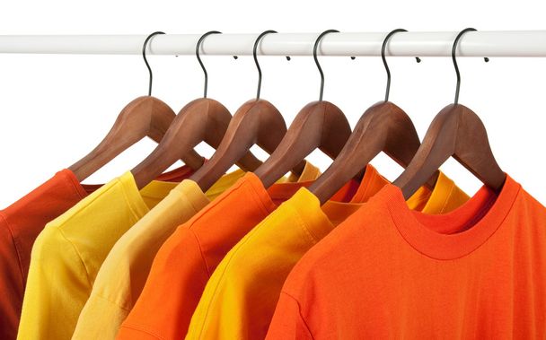 Gelbe und orangefarbene Hemden auf Kleiderbügeln - Foto, Bild