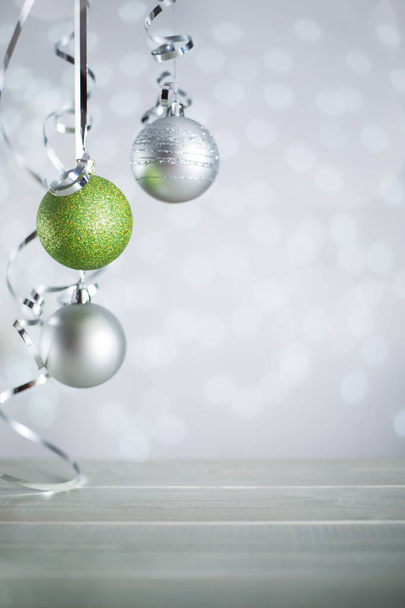 Ezüst és piros karácsonyi újévi labdák göndör szalagszalaggal íj felett csillogó bokeh fények háttér másolási hely szöveg - Fotó, kép