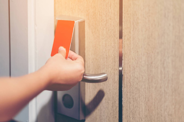 Closeup hand girl opens the door Hotel with electronic card lock on wooden door. Security, room service, privacy concept - Φωτογραφία, εικόνα