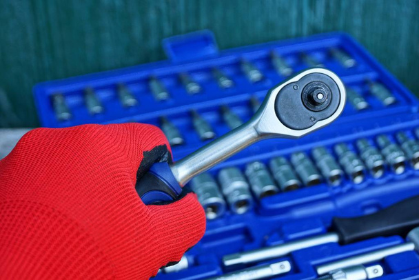 mano en guante rojo con un trinquete de herramienta sobre la caja de herramientas
 - Foto, imagen